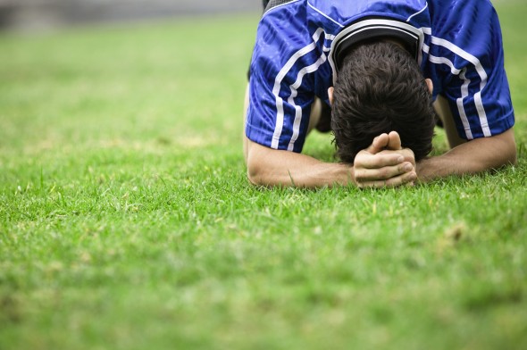 Soccer Player with Head Down on Grass